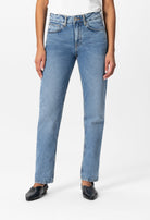 High-waisted light blue denim jeans, straight leg fit, worn with a simple white top and black slip-on shoes.