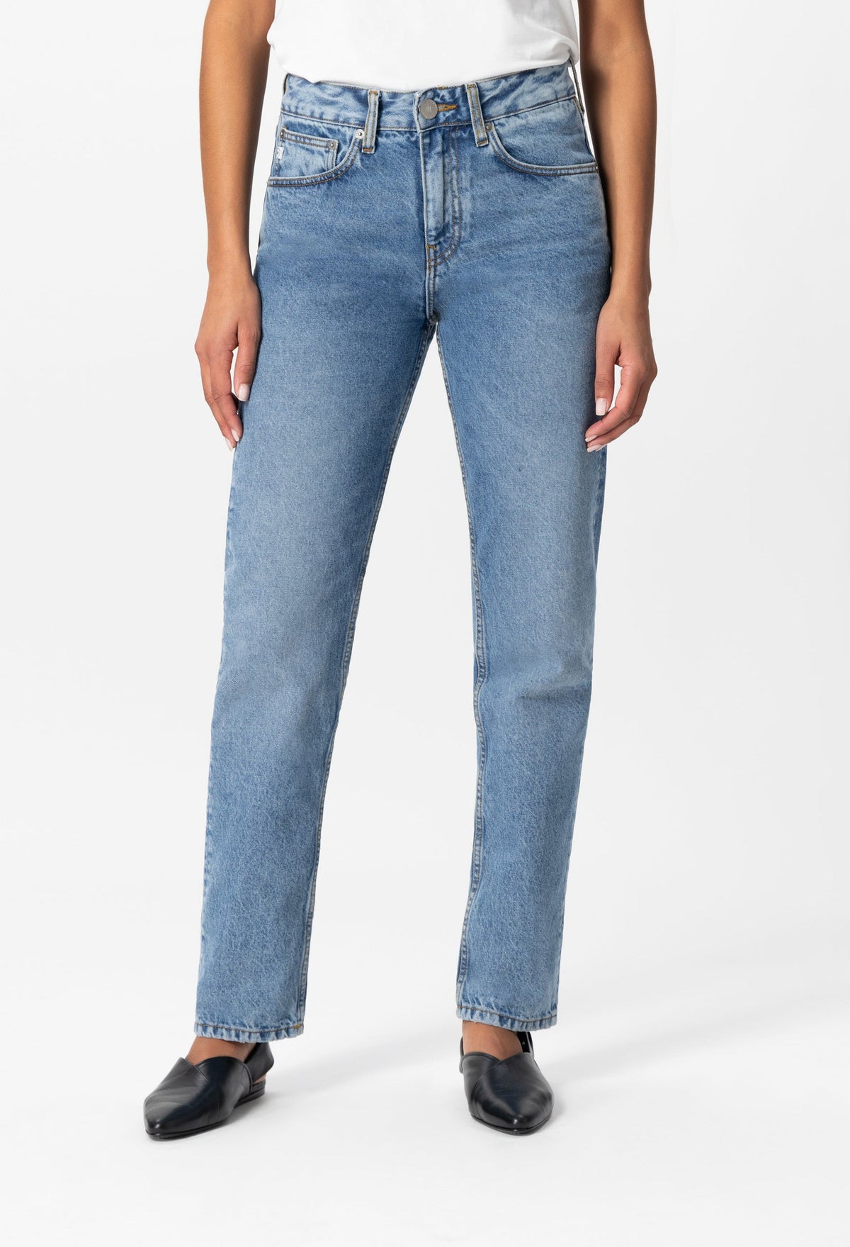 High-waisted light blue denim jeans, straight leg fit, worn with a simple white top and black slip-on shoes.