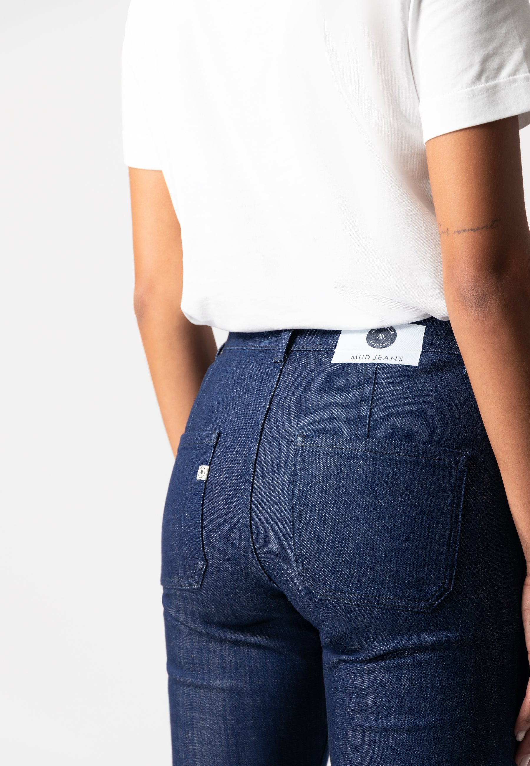 Dark blue MUD Jeans made from organic cotton, shown with a white short-sleeve shirt, highlighting sustainable fashion.