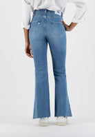 Light blue bootcut jeans with frayed hem, worn with a white shirt and white sneakers, showcasing casual fashion style.