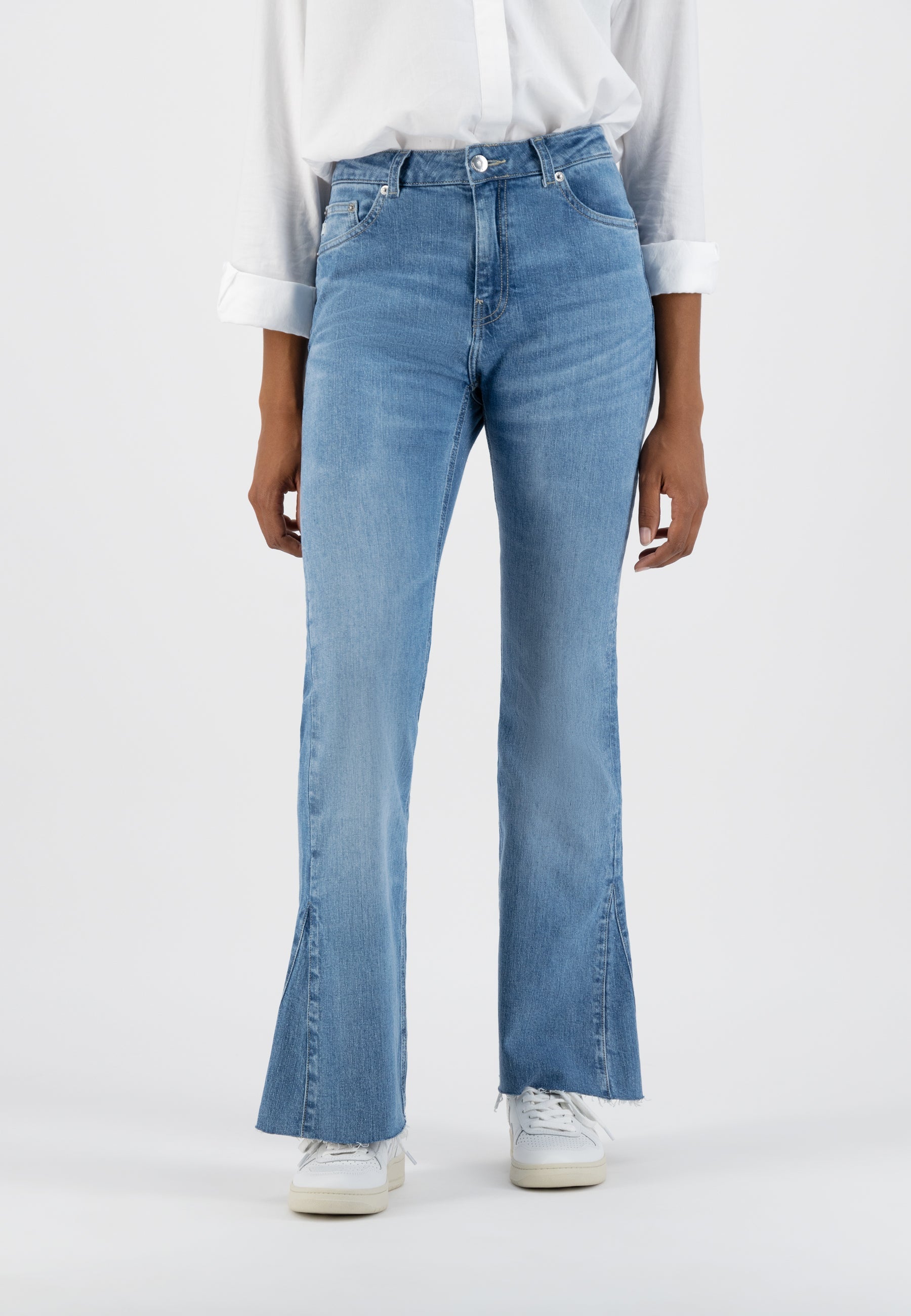 Flared light blue denim jeans paired with a crisp white shirt, showcasing a modern, casual style.