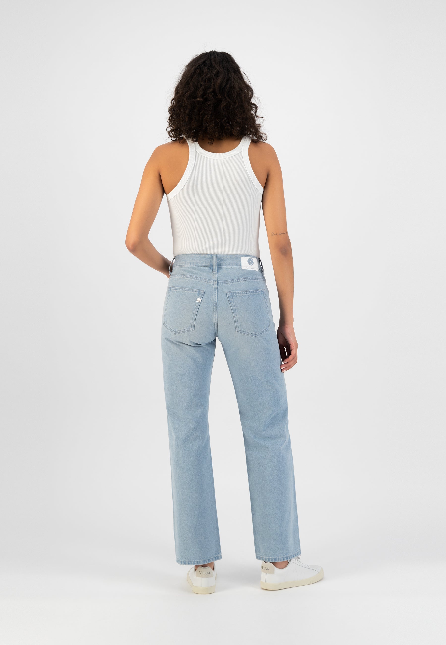 Light blue, high-waisted jeans paired with a white ribbed tank top, showcasing a casual and stylish rear view.