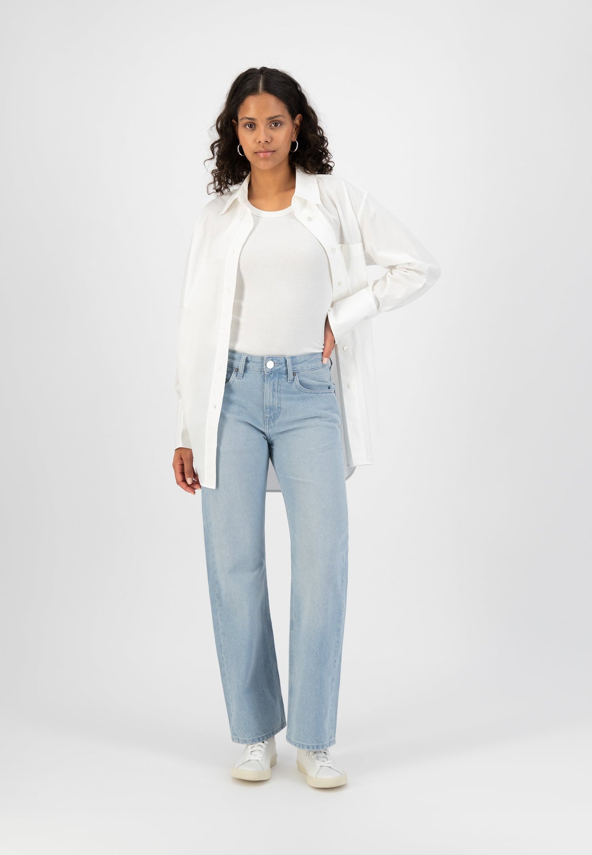 Casual outfit with light blue wide-leg jeans and a white ribbed tank top, paired with an oversized white button-up shirt.
