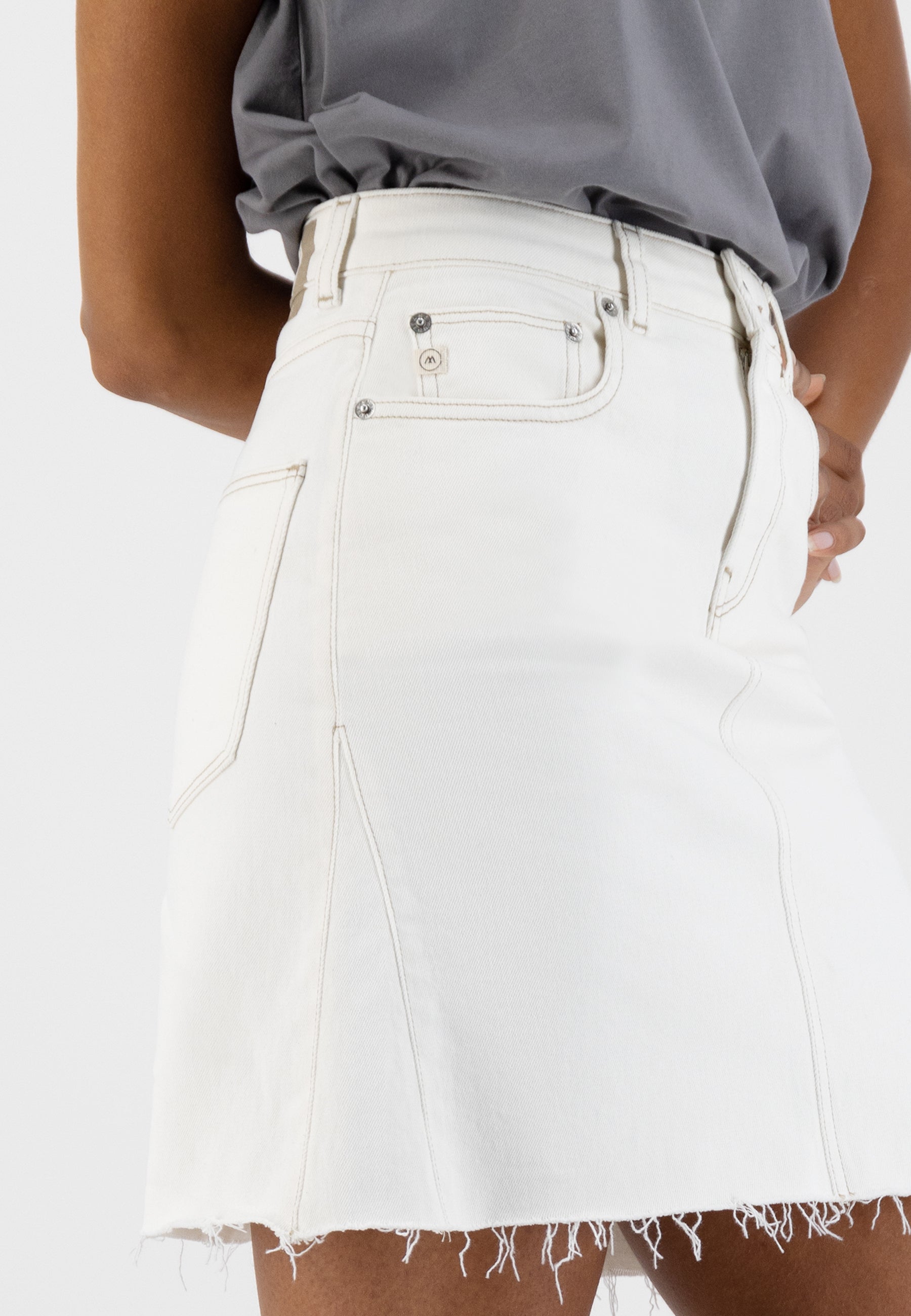 White denim A-line skirt with frayed hem, paired with a loose-fitting gray top, highlighting casual fashion style.