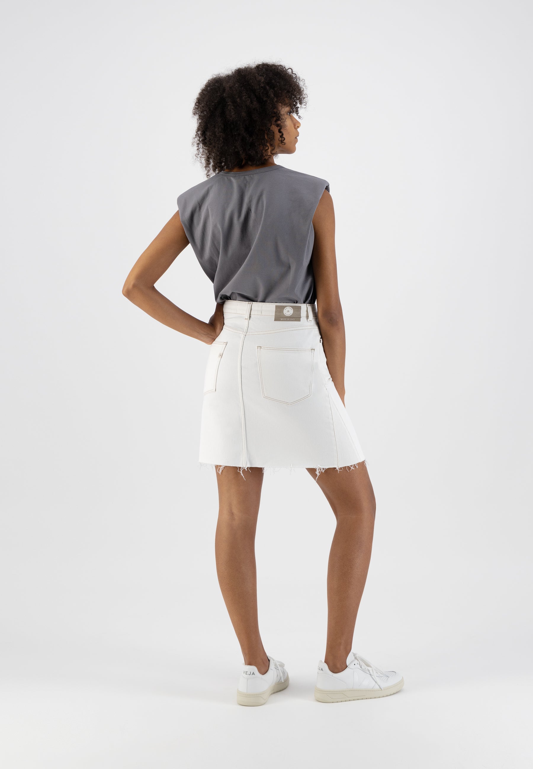 A-Line white denim skirt paired with a gray sleeveless top and white sneakers, showcasing casual chic summer fashion.