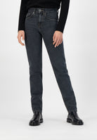 High-waisted, dark wash straight-leg jeans paired with a black long-sleeve top and black leather ankle boots.