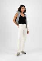 Casual outfit with white high-waisted jeans, black tank top, gray sweater over shoulders, and gray sneakers.