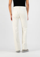 Back view of off-white denim jeans, straight leg fit, paired with casual sneakers and a black sleeveless top.