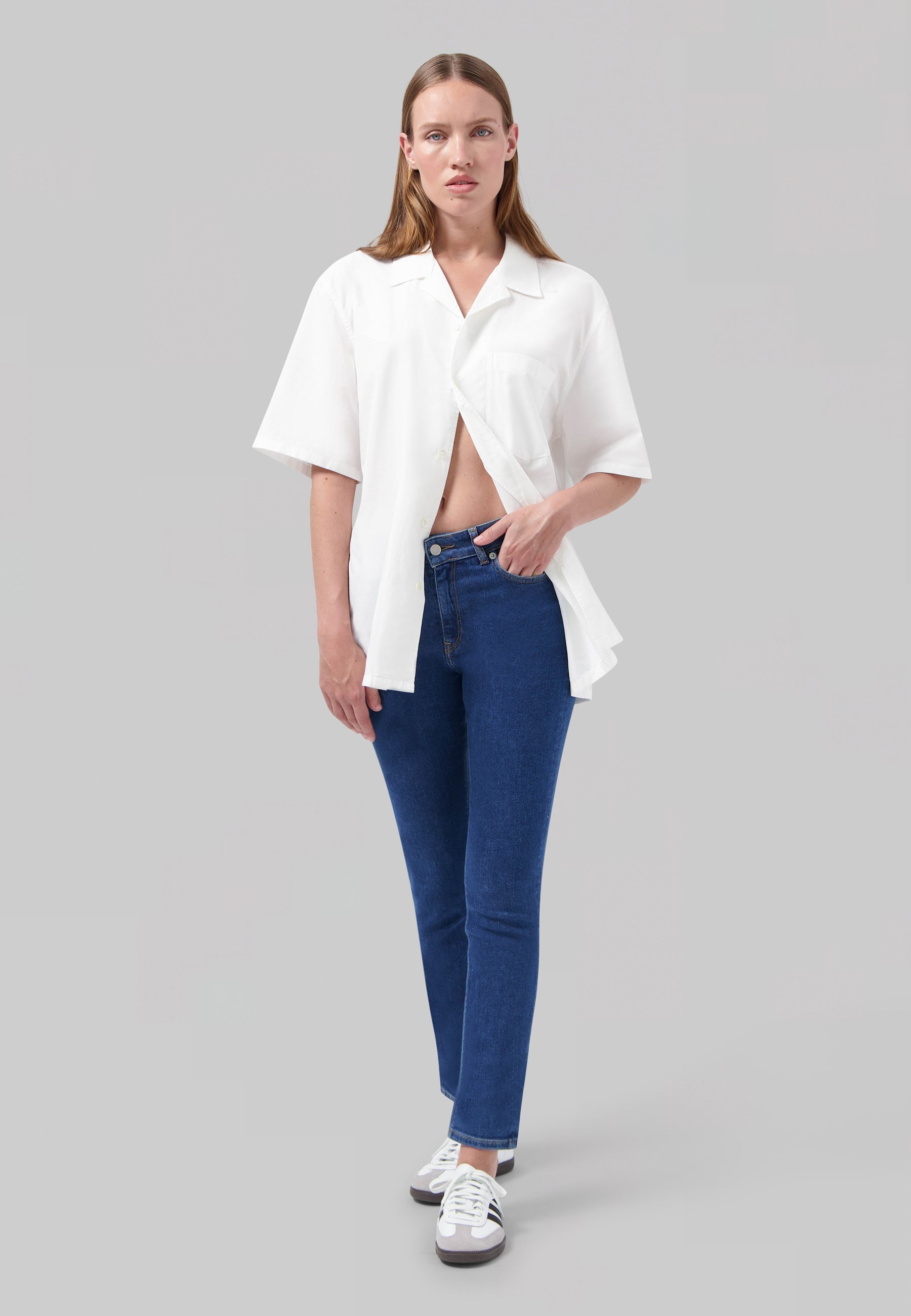 Casual blue jeans paired with a loose white button-up shirt, featuring a relaxed and modern minimalist style.
