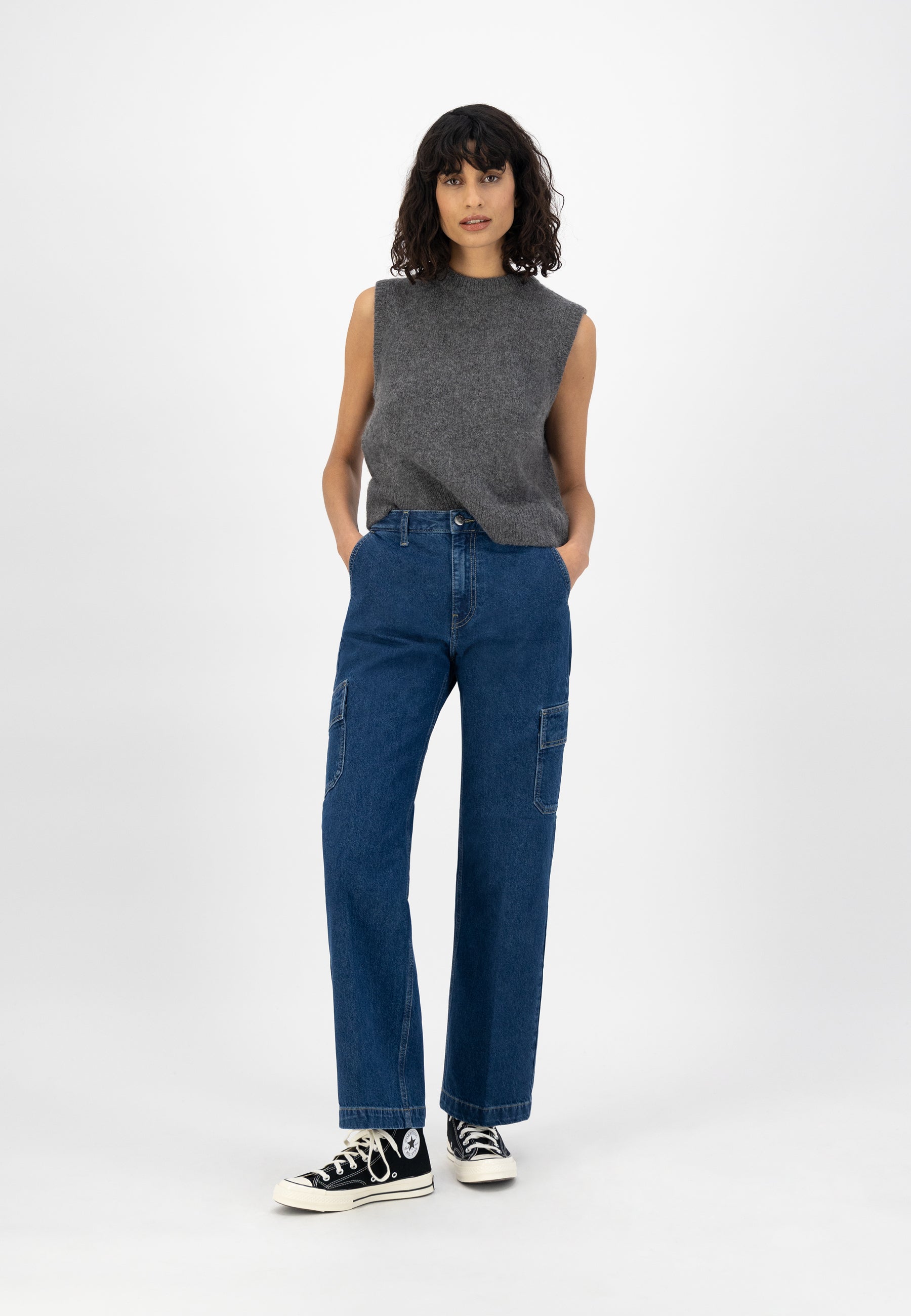 Casual outfit featuring a sleeveless gray sweater and blue wide-leg denim jeans, paired with black high-top sneakers.
