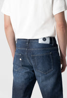 Sustainable MUD Jeans in dark blue organic denim, showcasing ethical fashion with a minimalist design and strong stitching.