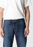Sustainable MUD Jeans in dark blue organic denim, showcasing ethical fashion with a minimalist design and strong stitching.