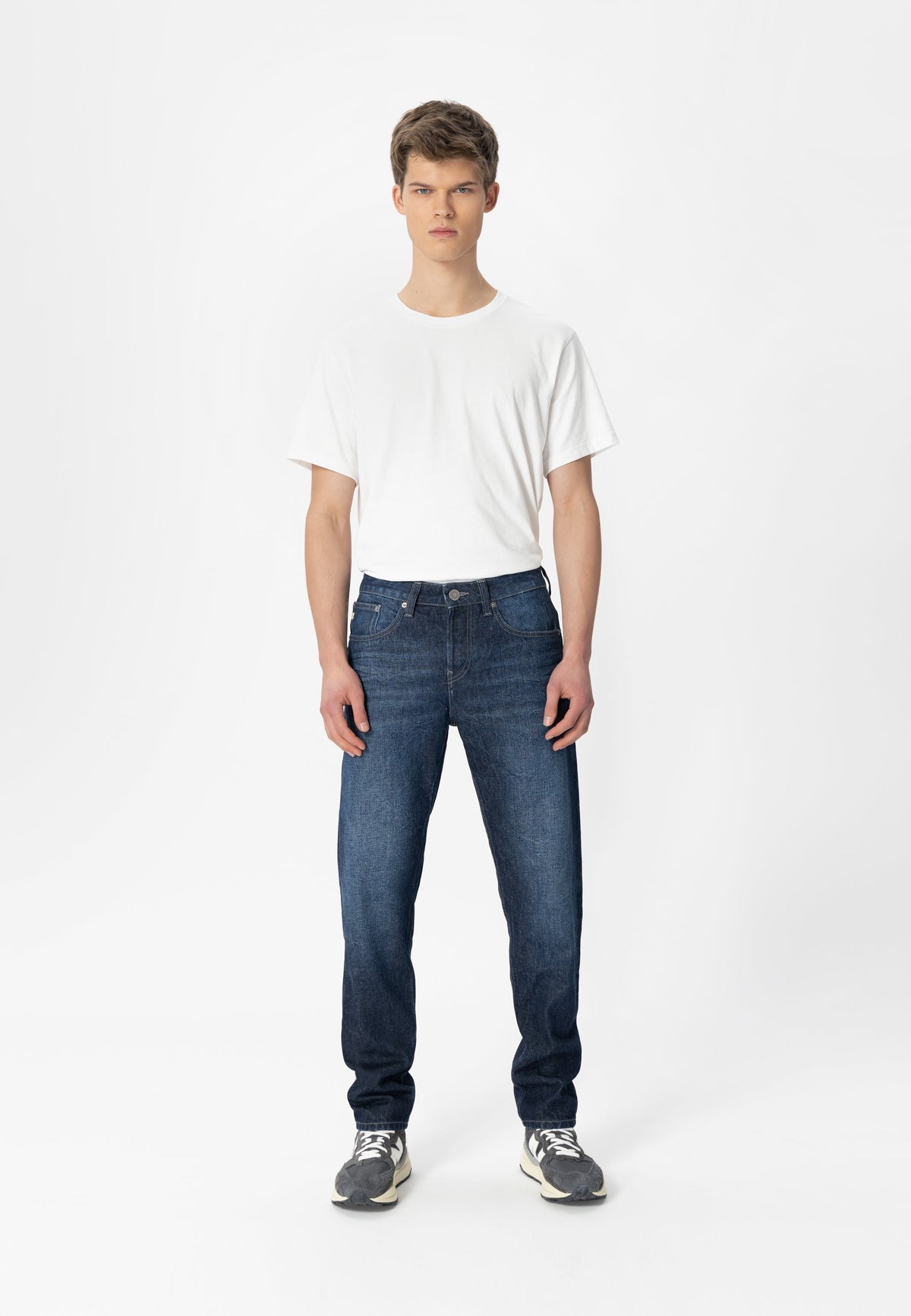 Sustainable MUD Jeans blue denim jacket made from ethical materials, worn with white top and beige pants.