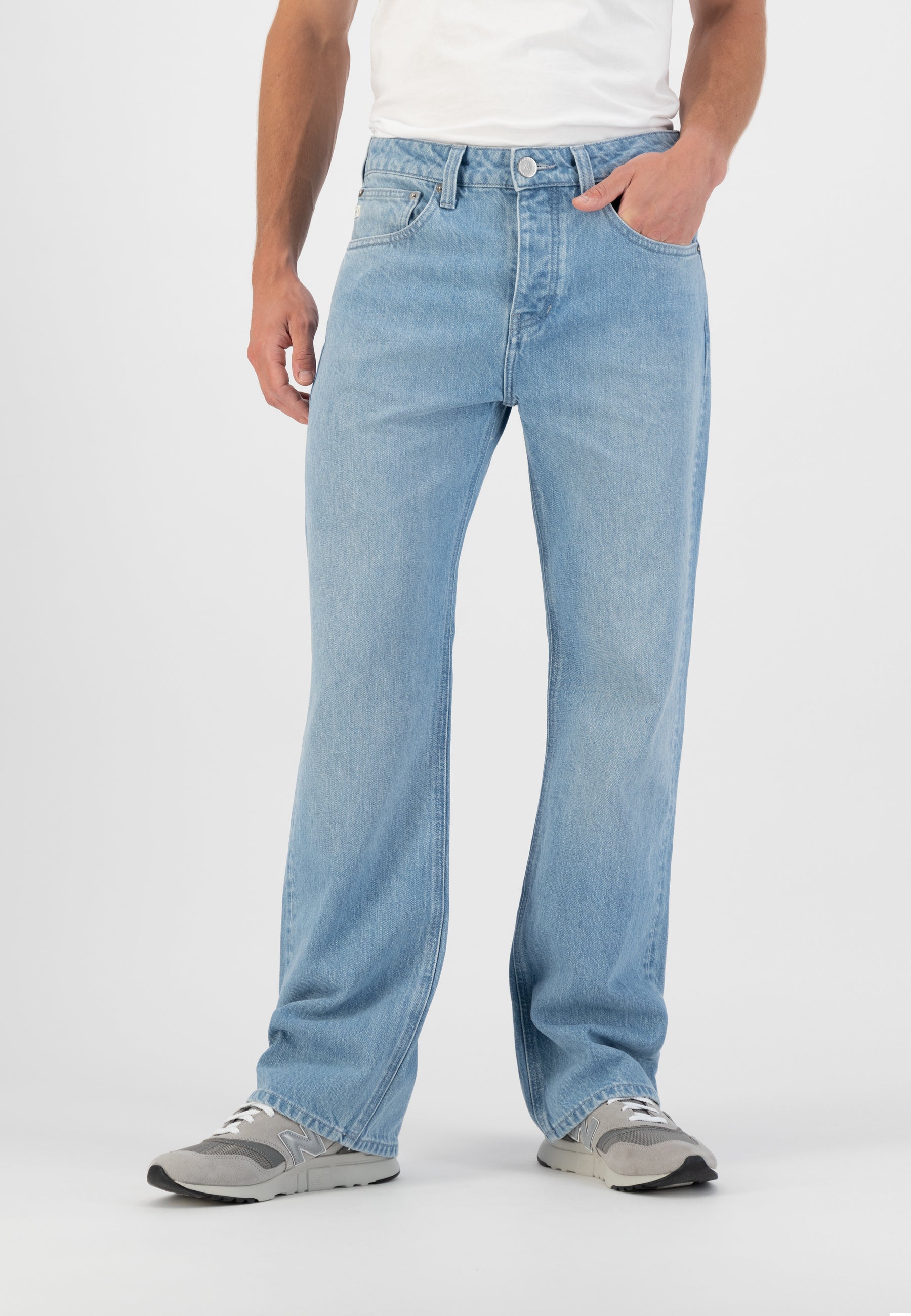 Sustainable MUD Jeans in light blue denim, crafted from organic cotton, paired with a white T-shirt and black cap.