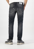 Sustainable MUD Jeans crafted from organic cotton in dark denim, classic fit, styled with a gray sweater.