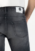 Sustainable MUD Jeans in dark gray, crafted from organic cotton, ethical fashion paired with a gray sweater.