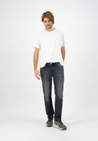Sustainable MUD Jeans in dark wash denim, featuring classic fit and eco-friendly design, worn with beige slip-ons.