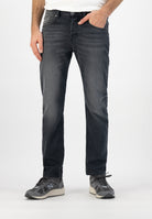 Sustainable MUD Jeans in gray denim, crafted ethically with organic cotton, paired with a gray sweater and white sneakers.
