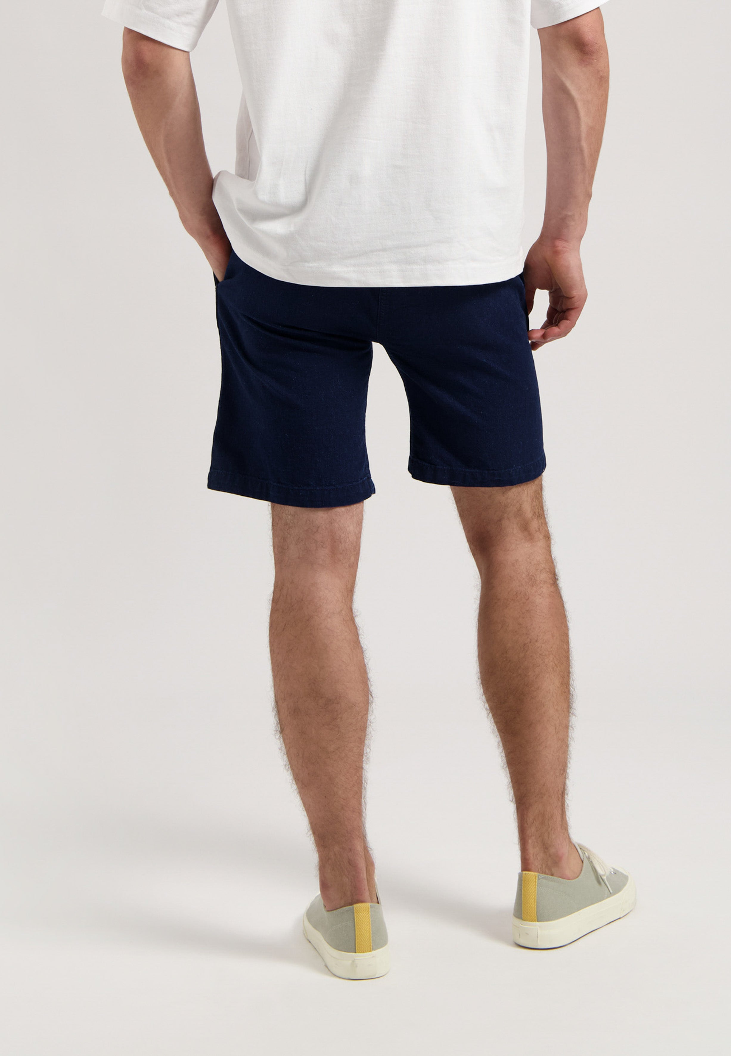 Sustainable MUD Jeans in dark blue denim, ethically made, worn with a plain white t-shirt and white sneakers.