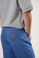 Sustainable MUD Jeans made from ethical materials, showcasing blue denim and classic stitching, worn with a black t-shirt.
