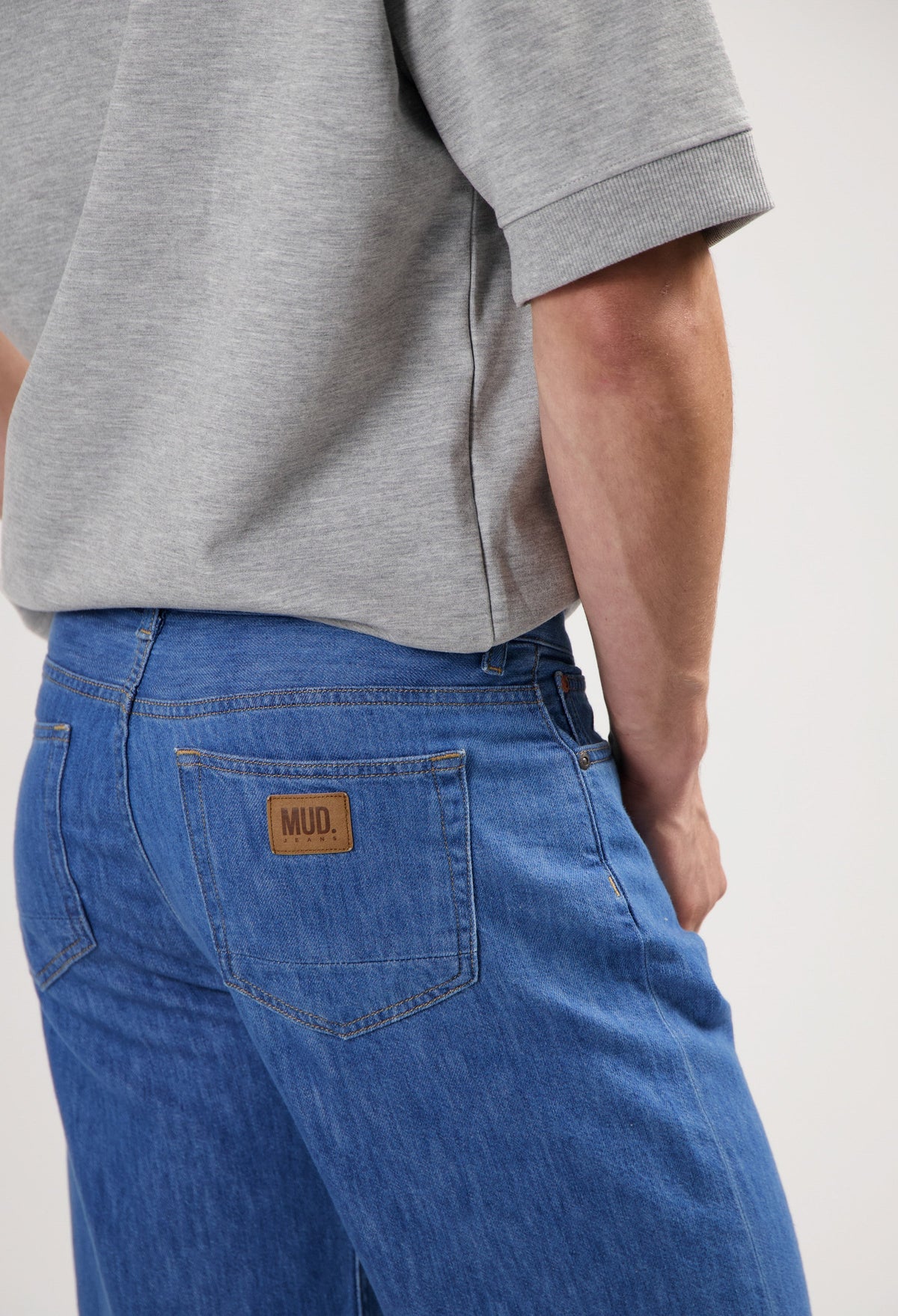 Sustainable MUD Jeans made from ethical materials, showcasing blue denim and classic stitching, worn with a black t-shirt.