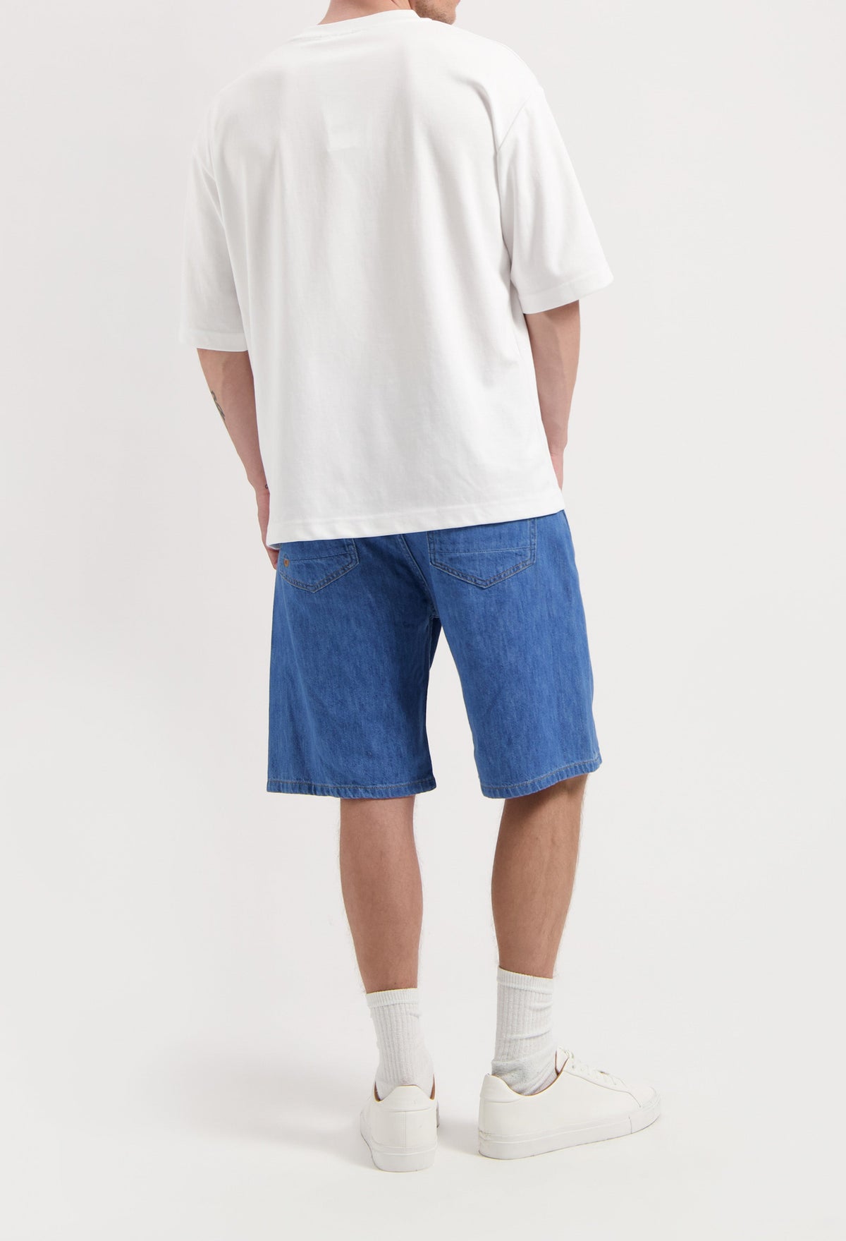 Sustainable MUD Jeans in dark blue denim, featuring classic back pockets, worn with a white cotton T-shirt.