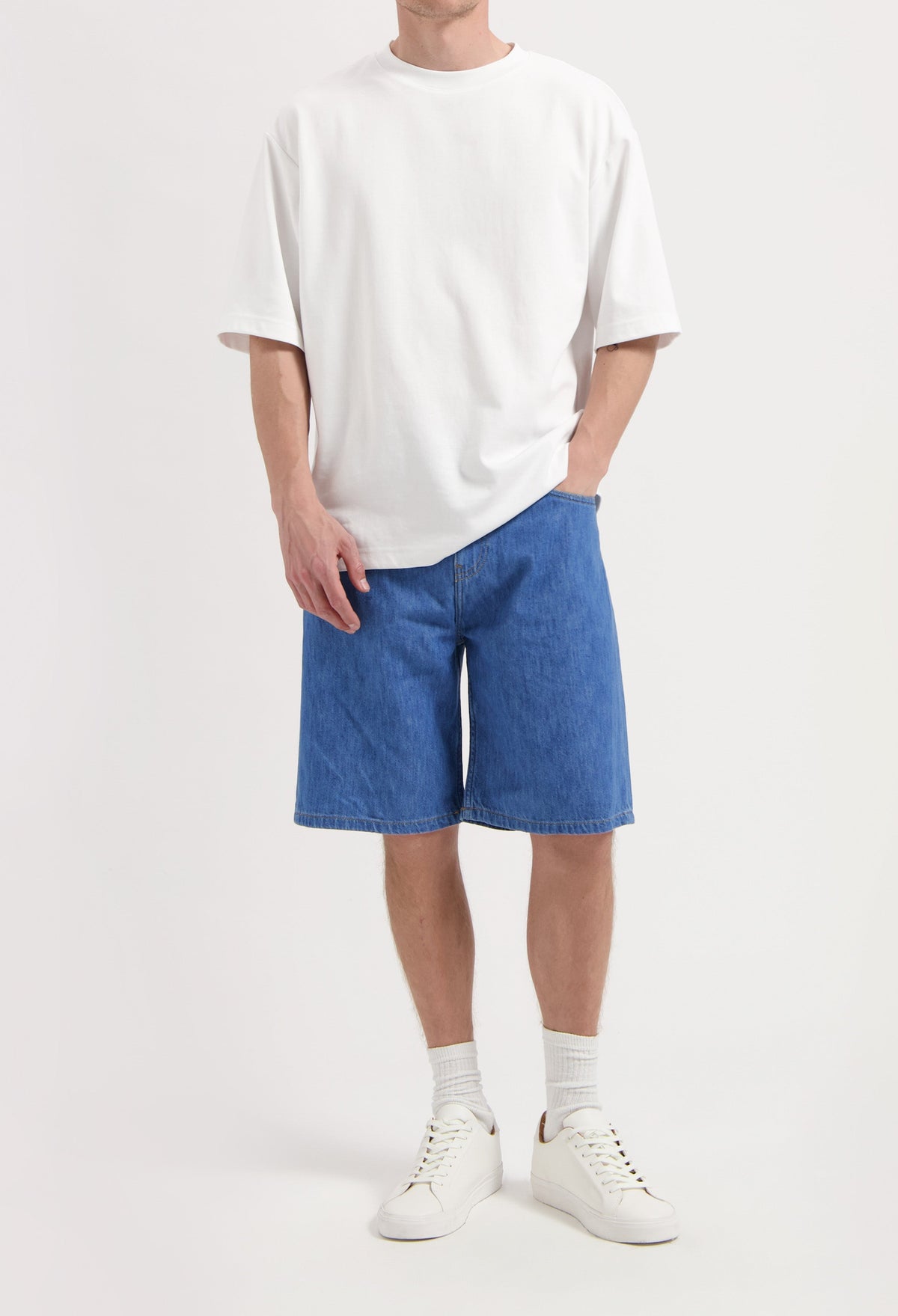 Sustainable MUD Jeans in classic blue denim, made from organic cotton for an ethical fashion choice, paired with black sneakers.