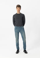 Sustainable MUD Jeans in mid-blue denim, styled with a white tee, crafted from ethical materials for casual wear.