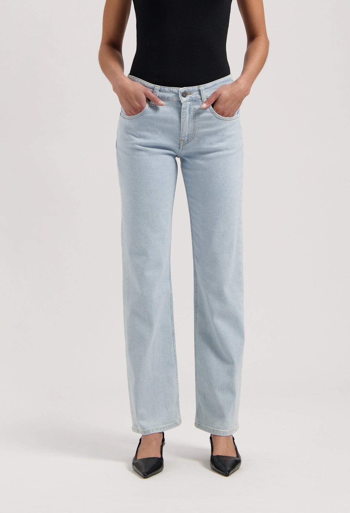 Light blue, high-waisted jeans in a classic fit, paired with a black sleeveless top and pointed black heels.