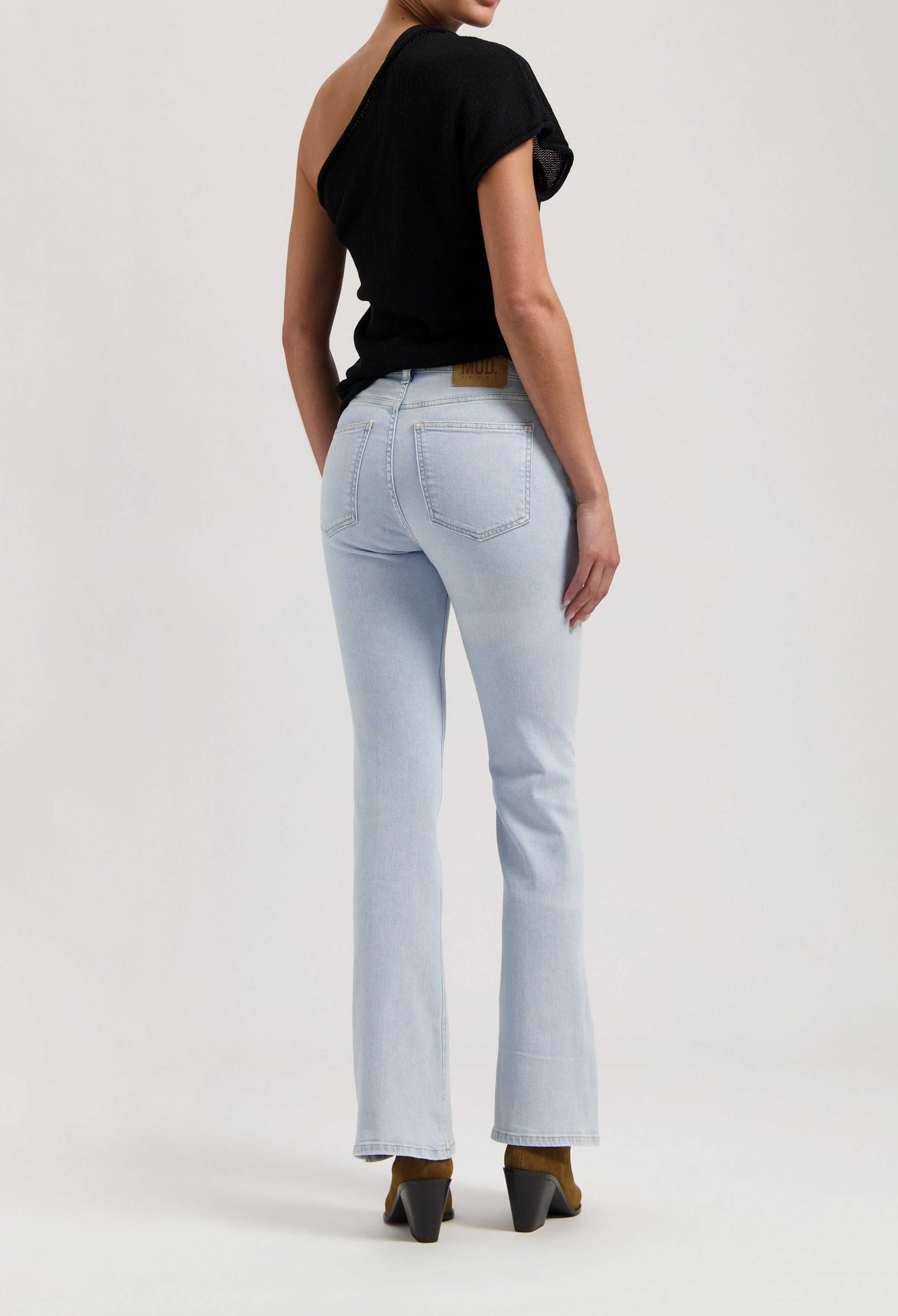 A stylish black off-shoulder top paired with light blue bootcut jeans, showcasing modern casual fashion.