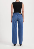 Back view of person wearing classic MUD Jeans in medium blue, wide-leg style, paired with a sleeveless black top.