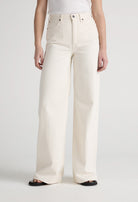 Wide-leg cream jeans in organic cotton, displaying high-waisted design paired with a simple white tank top.
