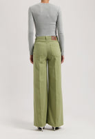 High-waisted, wide-leg MUD Jeans in light green organic cotton worn with a fitted gray long-sleeve top.