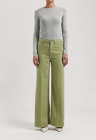 Light gray long-sleeve fitted top paired with wide-leg light green pants, worn with white pointed-toe shoes.