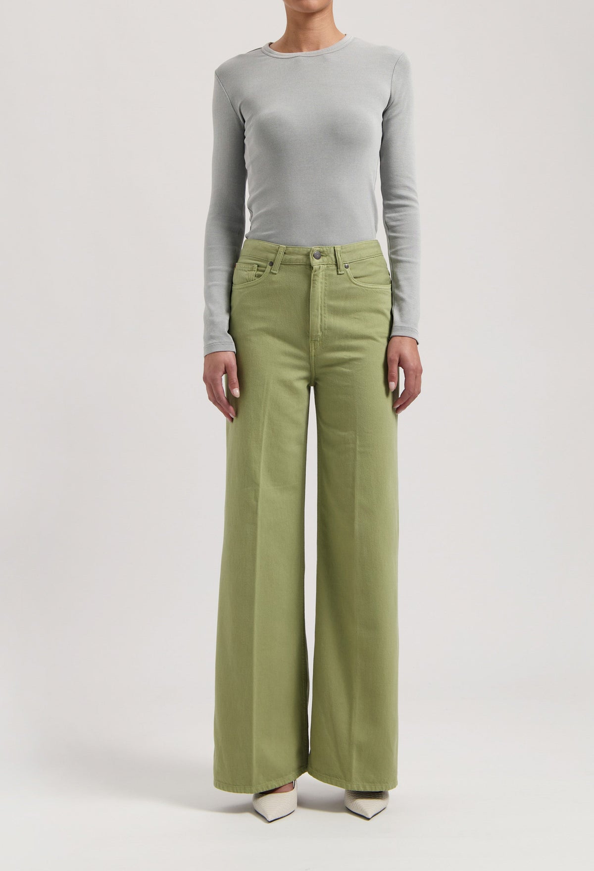 Light gray long-sleeve fitted top paired with wide-leg light green pants, worn with white pointed-toe shoes.