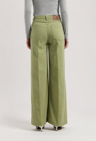 Wide-leg trousers in organic cotton, light green color, worn with a gray long-sleeve top, highlighting sustainable fashion.