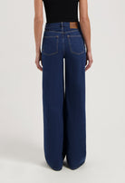 Wide-leg blue denim jeans from MUD Jeans made from organic cotton, shown from the rear, paired with a sleeveless black top.