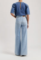 A denim ensemble with a back zipper blue top and light blue, wide-leg jeans, showcasing sustainable fashion.