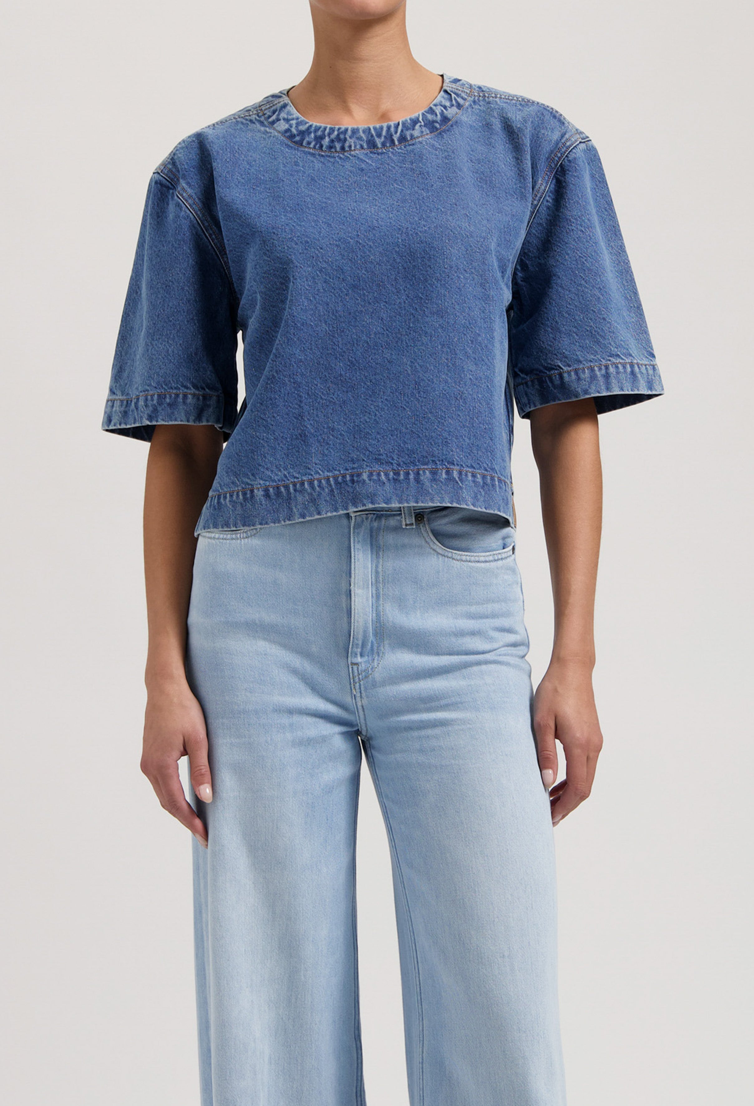Casual outfit featuring a blue denim short-sleeve top paired with high-waisted light blue wide-leg jeans.